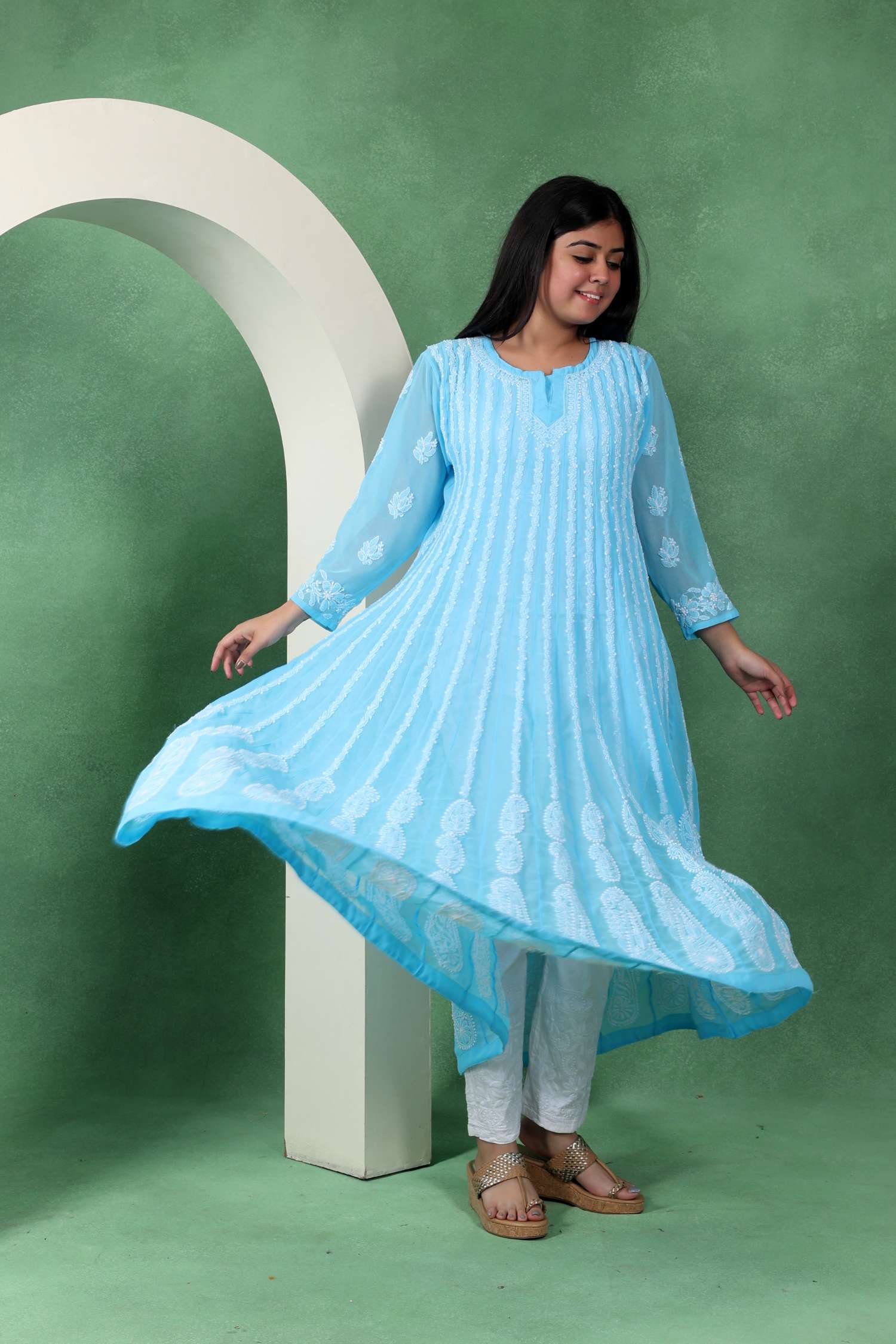 Woman wearing a light blue dress with white patterns on a green background